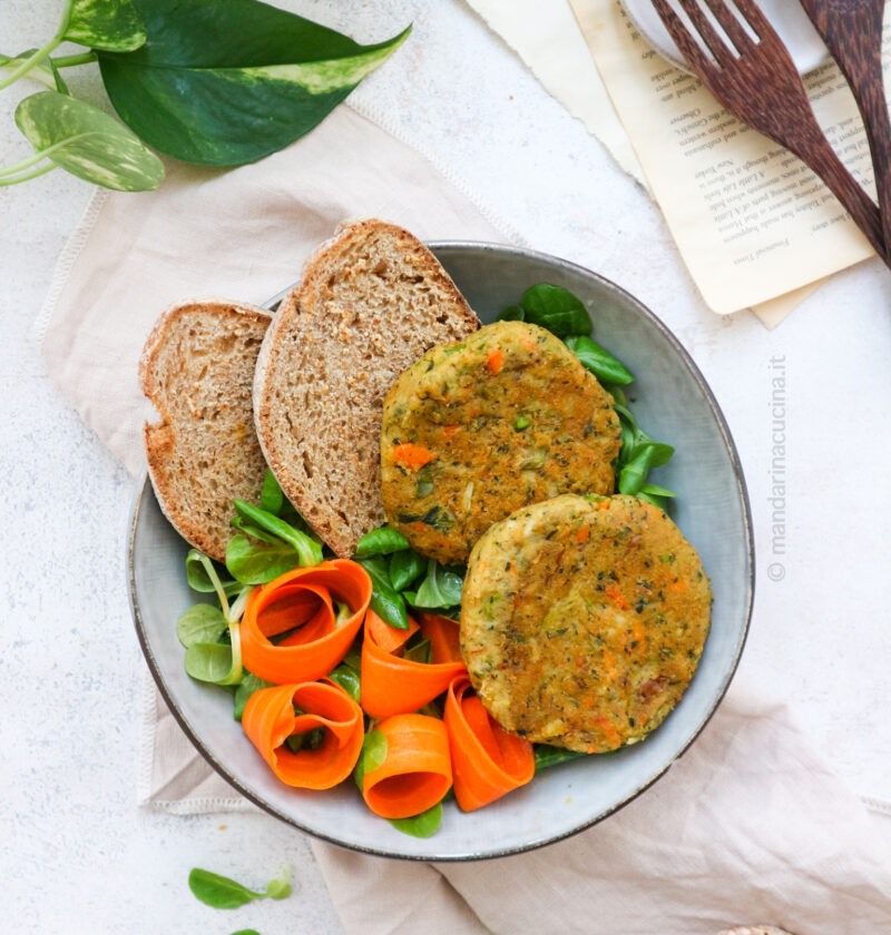 Nella foto i burger di minestrone su un piatto di insalata con fette di pane a decorare