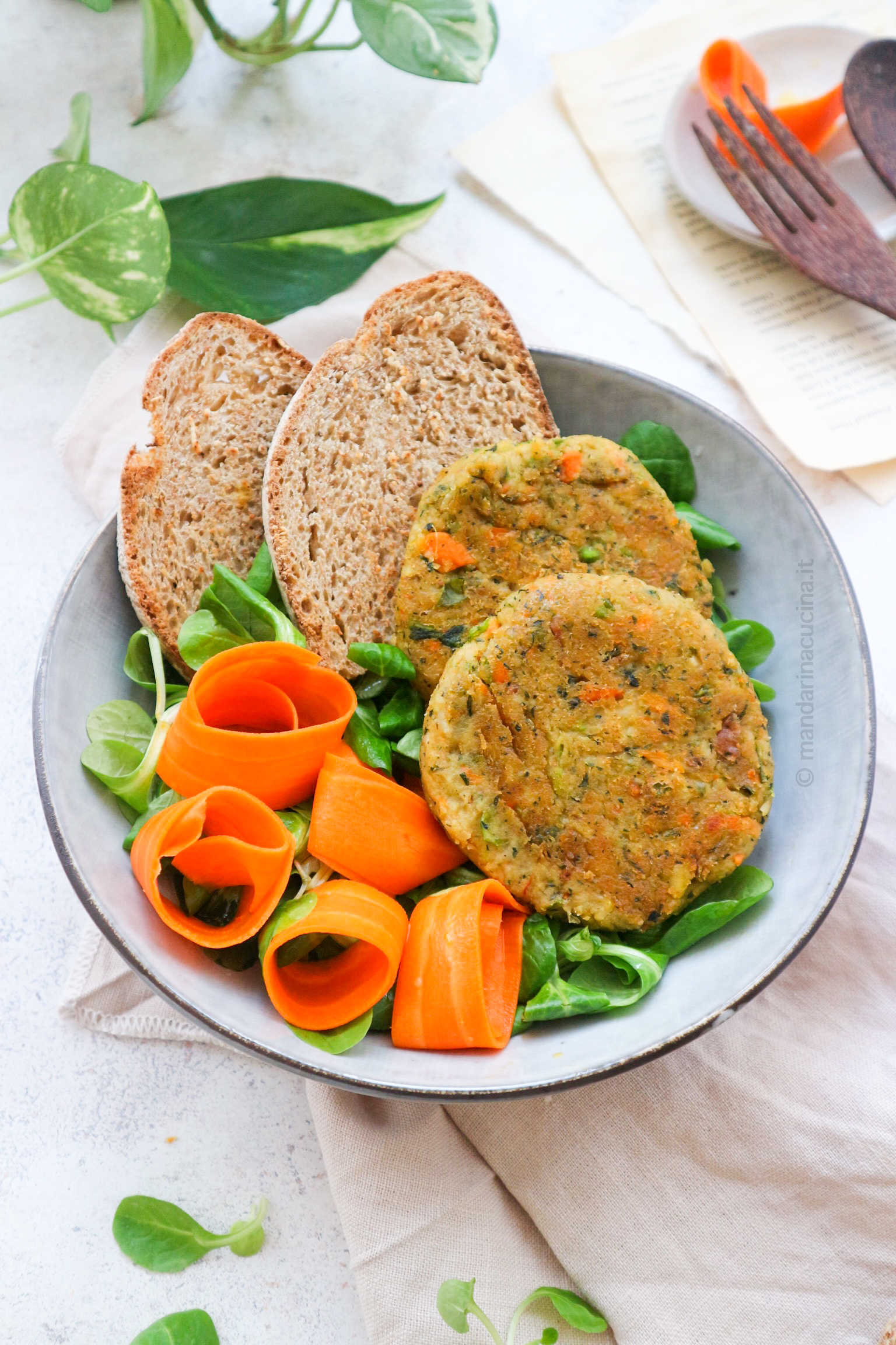 Nella foto i burger di minestrone visti più da vicino, su un piatto di insalata con fette di pane a decorare